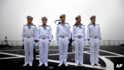 Chinese sailors stand on the deck of the naval training ship Qi Jiguang during a naval parade to commemorate the 70th anniversary of the founding of China's PLA Navy.