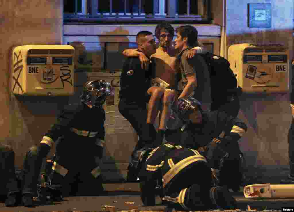 French fire brigade members aid an injured individual near the Bataclan concert hall following fatal shootings in Paris, France, Nov. 13, 2015. At least 130 people were killed in attacks.