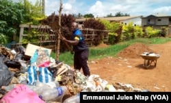 Stéphane ramasse les ordures sans protection pour dégager la voie publique obstrueés par les ordures ménagères au quartier Tropicana, à Yaoundé, au Cameroun, le 23 mai 2017. (VOA/Emmanuel Jules Ntap)