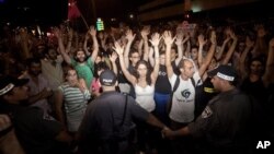 Para aktivis Israel mengangkat tangan mereka saat berunjuk rasa di Tel Aviv (24/6). Pihak berwenang telah menangkap sedikitnya 85 orang pasca bentrokan demonstran dan polisi dan pengrusakan di bank-bank di ibukota Israel ini.