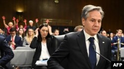 Državni sekretar SAD Antony Blinken na pretresu u Senatu o pomoći Ukrajini i Izraelu, dok se iza njega nalaze antiratni demonstranti, 31.oktobar 2023.