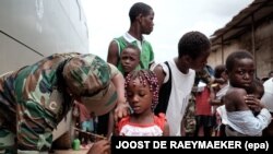 Un militaire angolais administre un vaccin de fièvre jaune à un enfant au marché 'quilometro 30', Luanda, Angola, 16 février 2016. epa/ JOOST dE Raeymaeker