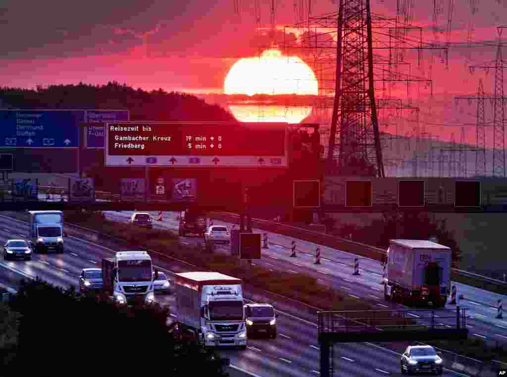 The sun rises as cars and trucks drive on a highway near Frankfurt, Germany.