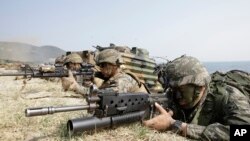 FILE – A South Korean Marine, right, and U.S. Marines aim their weapons near amphibious assault vehicles during the U.S.-South Korea joint landing military exercises as a part of the annual joint military exercise Foal Eagle between South Korea and the United States in Pohang, south of Seoul, South Korea, March 30, 2015. 