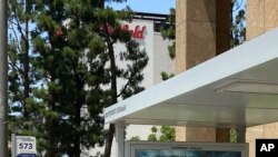 In this June 27, 2020 photo, people walk by a poster promoting the long-awaited Christopher Nolan film 'Tenet,' in Los Angeles.