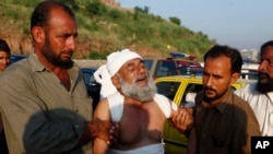 People help an injured victim who mourns for the loss of his family member at the site of plane crash in Rawalpindi, Pakistan, Tuesday, July 30, 2019. 