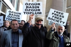 FILE - Turkish journalists cover their mouths with black ribbons before the trial of Can Dundar, the editor-in-chief of opposition newspaper Cumhuriyet and Erdem Gul, the paper's Ankara representative, outside the courthouse in Istanbul, April 1, 2016.