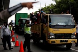 Seorang petugas polisi mengenakan masker ketika menjaga sebuah pos pemeriksaan jalan raya menyusul larangan pemerintah terhadap mudik untuk mencegah penyebaran wabah corona, di Bekasi, 24 April. (Foto: Reuters/Willy Kurniawan)