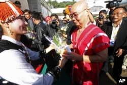 FILE - General Mutu Say Poe, second from right, chairman of Karen National Union (KNU), receives flowers from a woman upon his arrival to attend ethnic armed organizations conference in Laiza, Burma, Oct. 30, 2013.