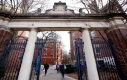 FILE - People walk through the gates leading to Harvard Yard, at Harvard University in Cambridge, Mass., Dec. 13, 2018.