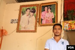 ស្វាមីជនរងគ្រោះ លោក សួន សាខេន ឈរនៅក្នុងផ្ទះ មុខ​រូបថតរៀបការ​របស់លោក​និងភរិយា​ដែលជា​ជនរងគ្រោះ ដែល​បាន​ស្លាប់​ដោយសារ​ការ​ធ្លាក់​ឈាម​បន្ទាប់​ពី​សម្រាល​កូន នៅ​ស្រុក​ចន្ទ្រា ខេត្តស្វាយរៀងកាលពីថ្ងៃទី៤ ខែកុម្ភៈ ឆ្នាំ២០១៩។ (ស៊ុន ណារិន/VOA)