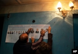 Election officials place pre-election leaflets at a polling station ahead of parliamentary elections in the village of Gusino, outside Smolensk, western Russia, Sept. 17, 2016.