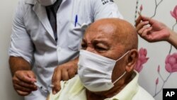 Jose Pereira Lima gets his shot of the COVID-19 vaccine produced by China's Sinovac Biotech Ltd., during the start of the vaccination in elderly people who live in public shelters, in Sao Paulo, Brazil, Jan. 19, 2021. 