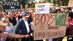 Anthony Albanese, Perdana Menteri Australia, mengenakan topi dan berdiri di dekat spanduk saat menghadiri pertemuan umum yang menyerukan langkah-langkah untuk mengakhiri kekerasan terhadap perempuan di Canberra pada Minggu, 28 April 2024. (Foto: via AP)