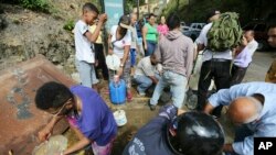 People collect water from an open pipeline during rolling blackouts, which affects the water pumps in people's homes and apartment buildings, in Caracas, Venezuela, March 11, 2019.