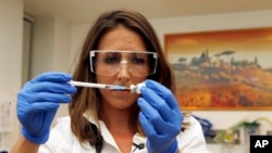 FILE - Dr. Felicity Hartnell, who is a clinical research fellow at Oxford University, holds a vial of an experimental vaccine against Ebola in Oxford, England, Sept. 17, 2014.
