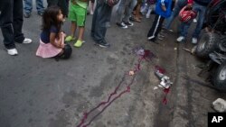 FILE - A girl closes her eyes as she sits at the scene of a murder in Tegucigalpa, Honduras, Dec. 1, 2014.