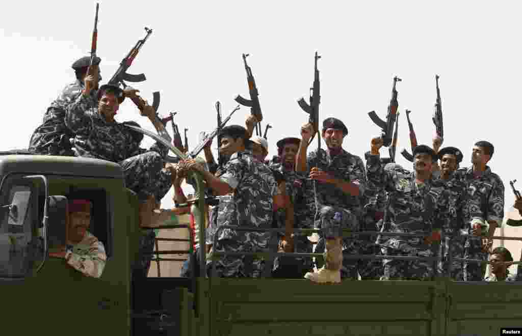 Shi&#39;ite volunteers who joined the Iraqi army to fight the Islamic State of Iraq and the Levant gesture with their weapons in Baghdad, June 18, 2014.