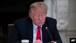 도널드 트럼프 미국 대통령이 18일 백악관에서 열린 경제 관련 회의 도중 스마트폰을 보고 있다.