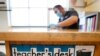 FILE - Des Moines Public Schools custodian Joel Cruz cleans a teacher's desk in a classroom at Brubaker Elementary School in Des Moines, Iowa, July 8, 2020.