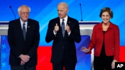 Democratic presidential candidates from left, Sen. Bernie Sanders, I-Vt., former Vice President Joe Biden and Sen. Elizabeth Warren, D-Mass., stand on stage Friday, Feb. 7, 2020, before the start of a Democratic presidential primary debate hosted by…
