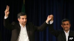 Iranian President Mahmoud Ahmadinejad, right, joins hands with his close ally Esfandiar Rahim Mashaei, as he flashes a victory sign, at the start of a press conference, May 11, 2013.