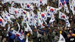 FILE - War veterans and members of conservative groups hold their national flags during a rally to call for unity between two Koreas in Seoul, South Korea, March 1, 2015. 