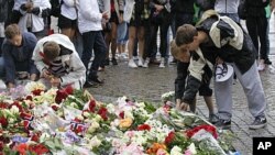 Norwegian boys place flowers on the cobble stones of the market square outside the Oslo cathedral to mourn the victims of a bomb blast in the capital and a rampage on an island in the countryside July 23, 2011
