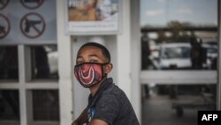 A boy wears a face mask as a preventive measure against the spread of the COVID-19 coronavirus outside Makro in Soweto, Johannesburg, South Africa, on March 24, 2020.