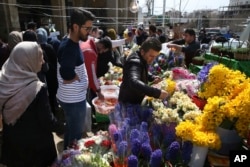 A flower seller picks flower for his customer at Tajrish traditional bazaar in northern Tehran, Iran, ahead of the Iranian New Year, or Nowruz, meaning "new day," March 18, 2017.