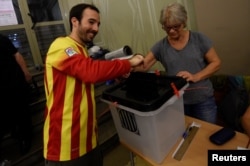 A man, wearing a shirt with the colors of Catalan regional flag, casts his vote in a polling station of the banned separatist referendum in Barcelona, Spain, Oct. 1, 2017.