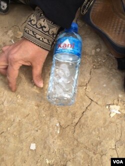Not wanting to show her face on camera for fear of IS-violence against her family, grandmother Haifa Hamid makes a map of New Mosul with a water bottle, demonstrating where entire blocks have been flattened on March 26, 2017 in Hammam Alil, Iraq. (H.Murdock/VOA)