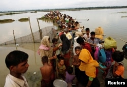 Rohingya refugees wait for boat to cross a canal after crossing the border through the Naf river in Teknaf, Bangladesh, Sept. 7, 2017.