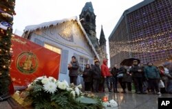 A man takes a picture of candles and flowers after the reopening of the Christmas market at the Kaiser Wilhelm Memorial Church in Berlin, Germany, Dec. 22, 2016, three days after a truck ran into the crowded market and killed several people.
