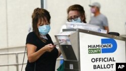 FILE - A voter drops off her absentee ballot during early voting at the Park Slope Armory YMCA, in the Brooklyn borough of New York, Oct. 27, 2020.