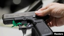 ຜູ້ຊາຍຄົນນຶ່ງຖືປືນສັ້ນ ຍີ່ຫໍ້ ກລັອກ ໃນລະຫວ່າງກອງປະຊຸມຂອງສະມາຄົມປືນຍາວແຫ່ງຊາດ, ນະຄອນ ດາລລາສ, ລັດ ເທັກຊັສ, 6 ພຶດສະພາ 2018. 