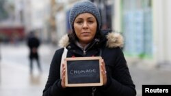 FILE - Malika Etchekopar-Etchart, unemployed, holds a blackboard with the word "chomage" (unemployment), the most important election issue for her, as she poses for Reuters in Chartres, France.