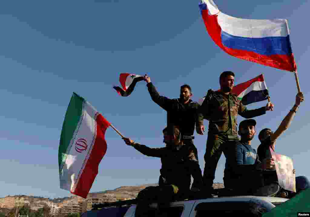 Syrians wave Iranian, Russian and Syrian flags during a protest against U.S.-led air strikes in Damascus, Syria, April 14, 2018.