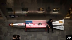 Seorang pria duduk pada gimmick promosi berbentuk bom dan bendera AS di luar toko pakaian AS di sebuah pusat perbelanjaan di Beijing, Kamis, 5 Juli 2018.