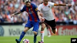 Enzo Perez de Valence, à droite, en duel avec Lionel Messi du FC Barcelone, à gauche, lors du match de football de la Liga espagnole entre Valence et le FC Barcelone au stade Mestalla à Valence, en Espagne, 22 octobre 2016. 