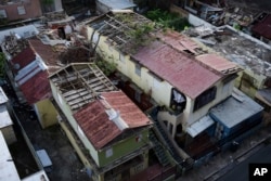 In this Nov. 15, 2017 photo, some roofs damaged by Hurricane Maria are still exposed to rainy weather conditions, in San Juan, Puerto Rico.