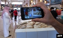 FILE - A gamer uses the Pokemon Go application on his mobile in the main fish market in Kuwait City, July 14, 2016.