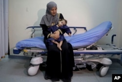 In this Monday, March 5, 2018 photo, Syrian refugee Sara al-Matoura holds her one-year-old daughter, Eman, before her surgery at a hospital in Amman, Jordan.