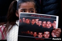 A girl holds up a poster with pictures of the 21 Egyptian Coptic Christians beheaded by Islamic State in Libya, as they gather in a gesture to show their solidarity, in front of the Egyptian embassy in Amman, February 17, 2015.