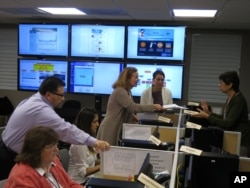 FILE - Workers from the Puerto Rico Health Department and U.S. Centers for Disease Control and Prevention review Zika-related data collected by the island's health dept and CDC workers in San Juan, Puerto Rico, Feb. 24, 2016.