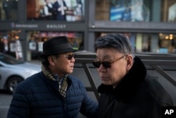 Song Hong, left, walks with his childhood friend Choi Kyu-Sik in downtown Gangneung, South Korea, Feb. 12, 2018.