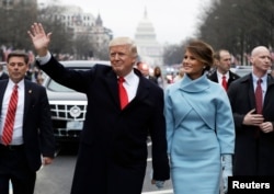 President Donald Trump waves as he walks with first lady Melania Trump and son Barron during the inauguration parade on Pennsylvania Avenue in Washington, Jan. 20, 2017.