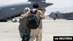 A family walks towards a US Air Force Boeing C-17 Globemaster III during an evacuation at Hamid Karzai International Airport, Afghanistan, Aug. 22, 2021. (US Marine Corps photo)