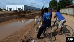This photo taken on July 9, 2024 shows villagers, watching excavators being used on the construction of the Funan Techo canal along the Prek Takeo channel in Kandal province.