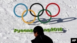 FILE - A man walks by the Olympic rings with a sign of 2018 Pyeongchang Olympic Winter Games, in Pyeongchang, South Korea, Feb. 3, 2017. 